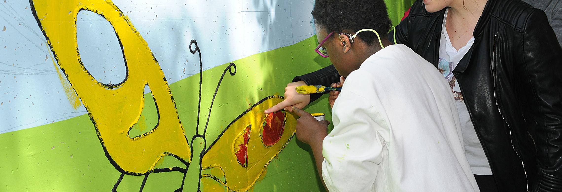 Image d'une élève du CPHV dessine sur la fresque du bâtiment